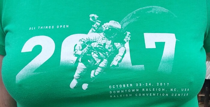 In All Things Open's 2017 T-shirt, it appears that the spaceman is taking his chair for a ride in space.