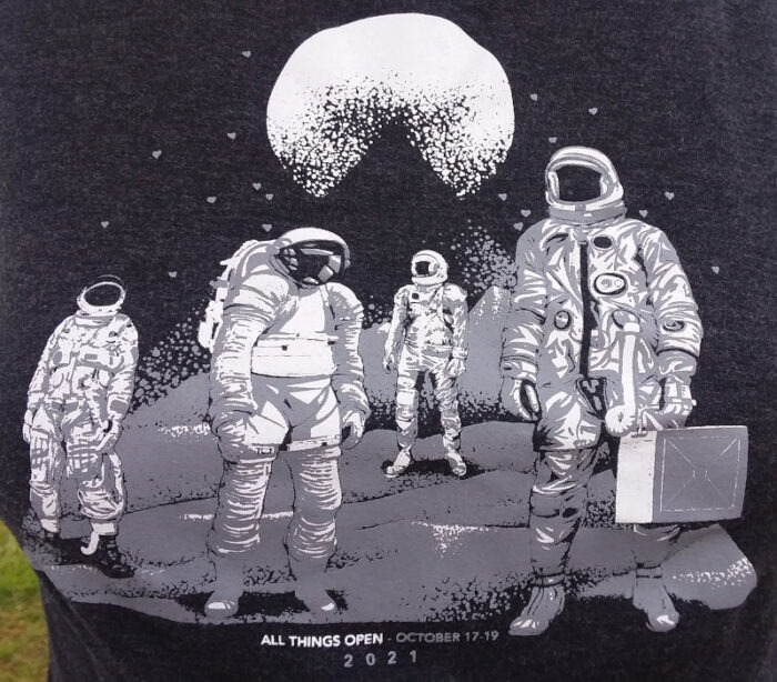 All Things Open 2021 T-shirt design that features four spacemen, apparently walking on the surface of the moon.