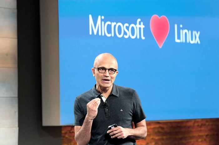 Satya Nadella giving talk in fron of a Microsoft Loves Linux display.