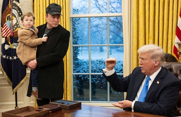 President Donald Trump with reporters and Elon Musk, who is holding his young son named X Æ A-Xii in the White House Oval Office on February 11, 2025.