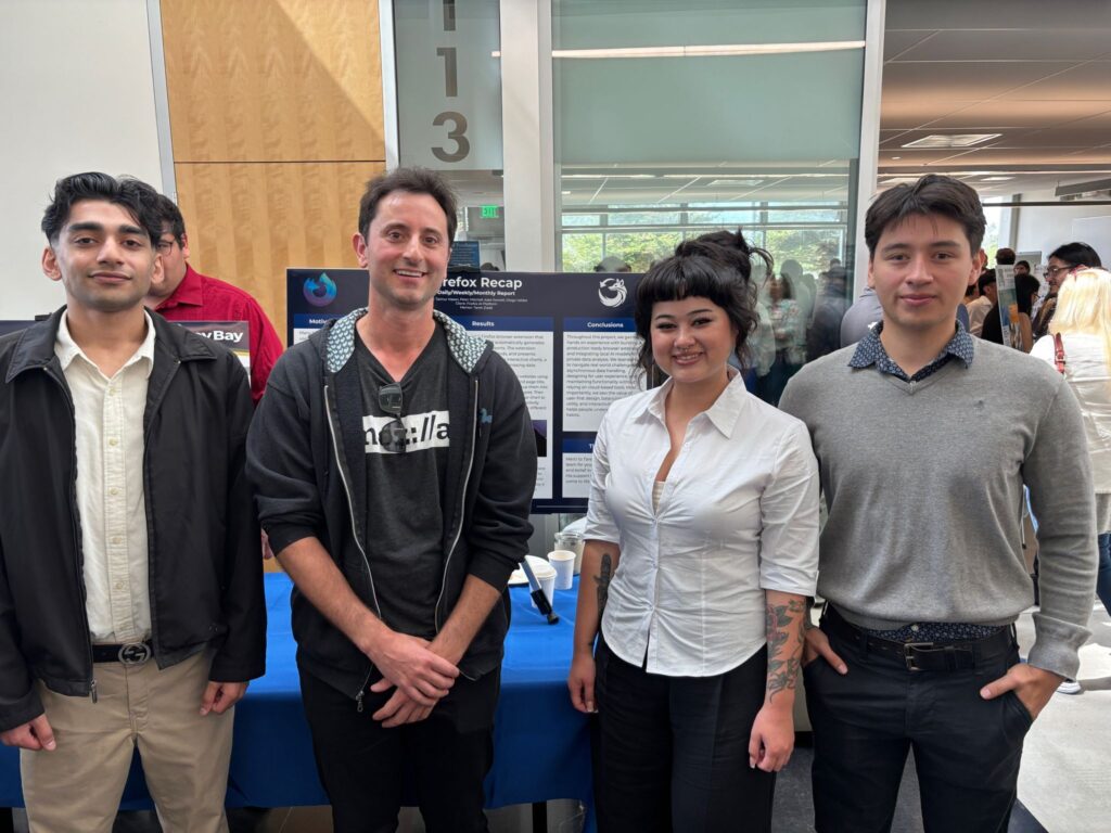 Four people standing in front of a Firefox Recap project display at California State University, Monterey Bay. From left to right: Taimur Hasan, Mozilla community manager Matt Cool, Kate Sawtell, and Diego Valdez.